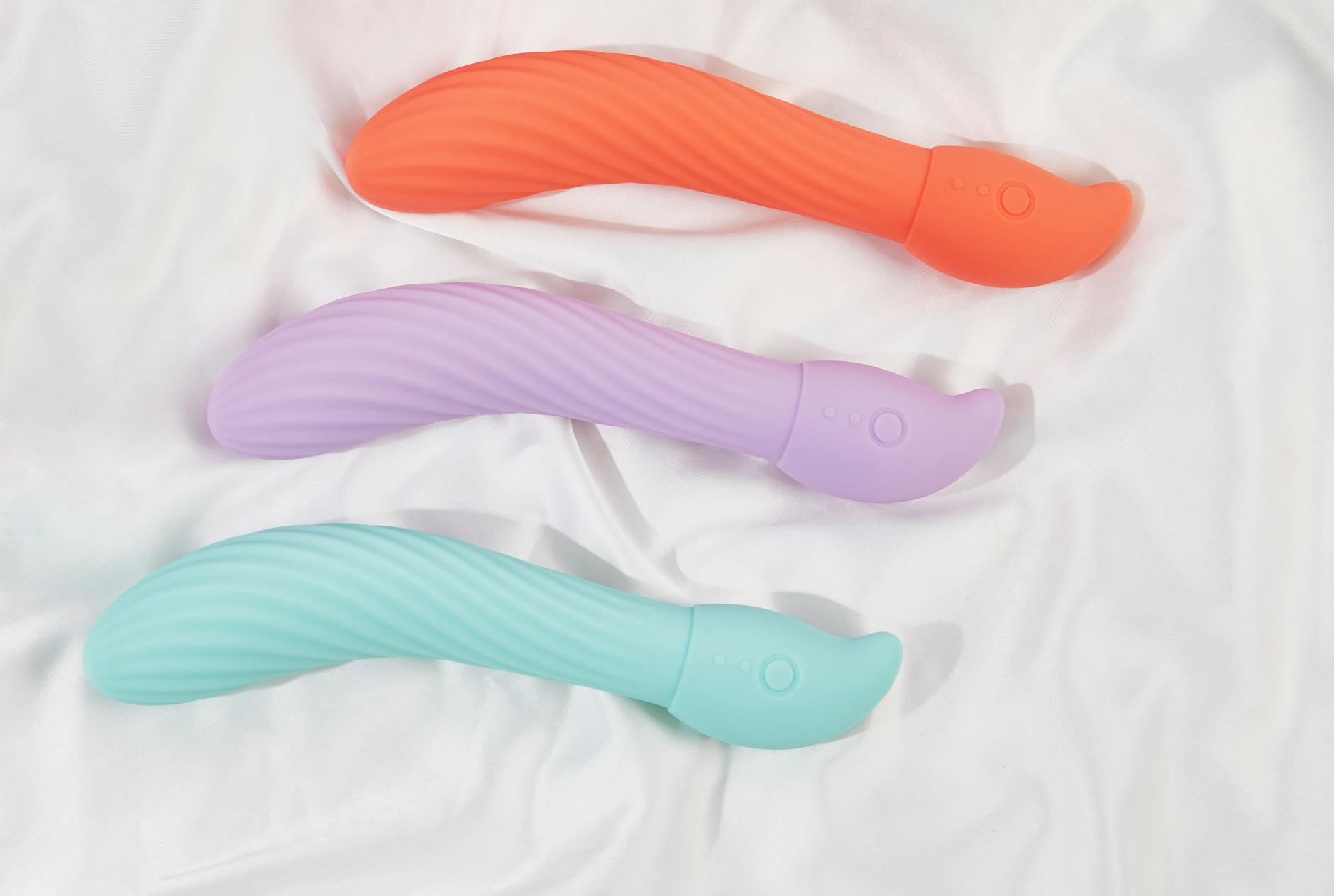 Three colorful lemon vibrators arranged on white fabric, highlighting their smooth suction-cup texture