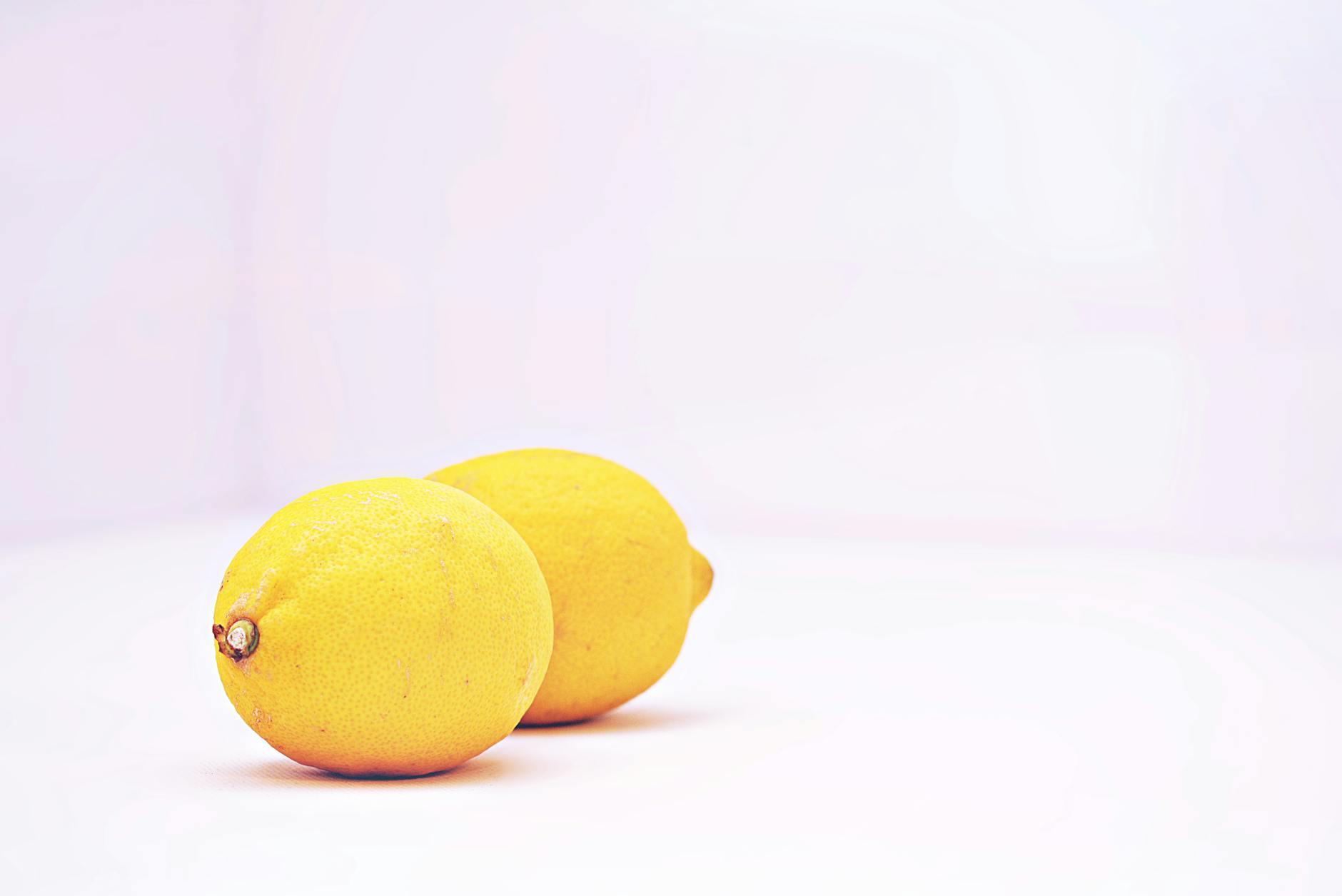 Two vibrant lemons on a minimalist white background, representing freshness and gentle stimulation