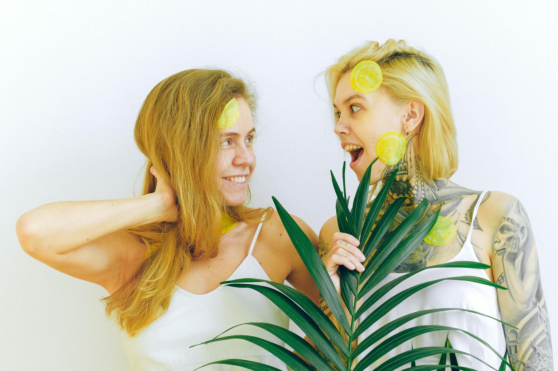Hand holding a fresh lemon on a soft pink background with three additional lemons nearby