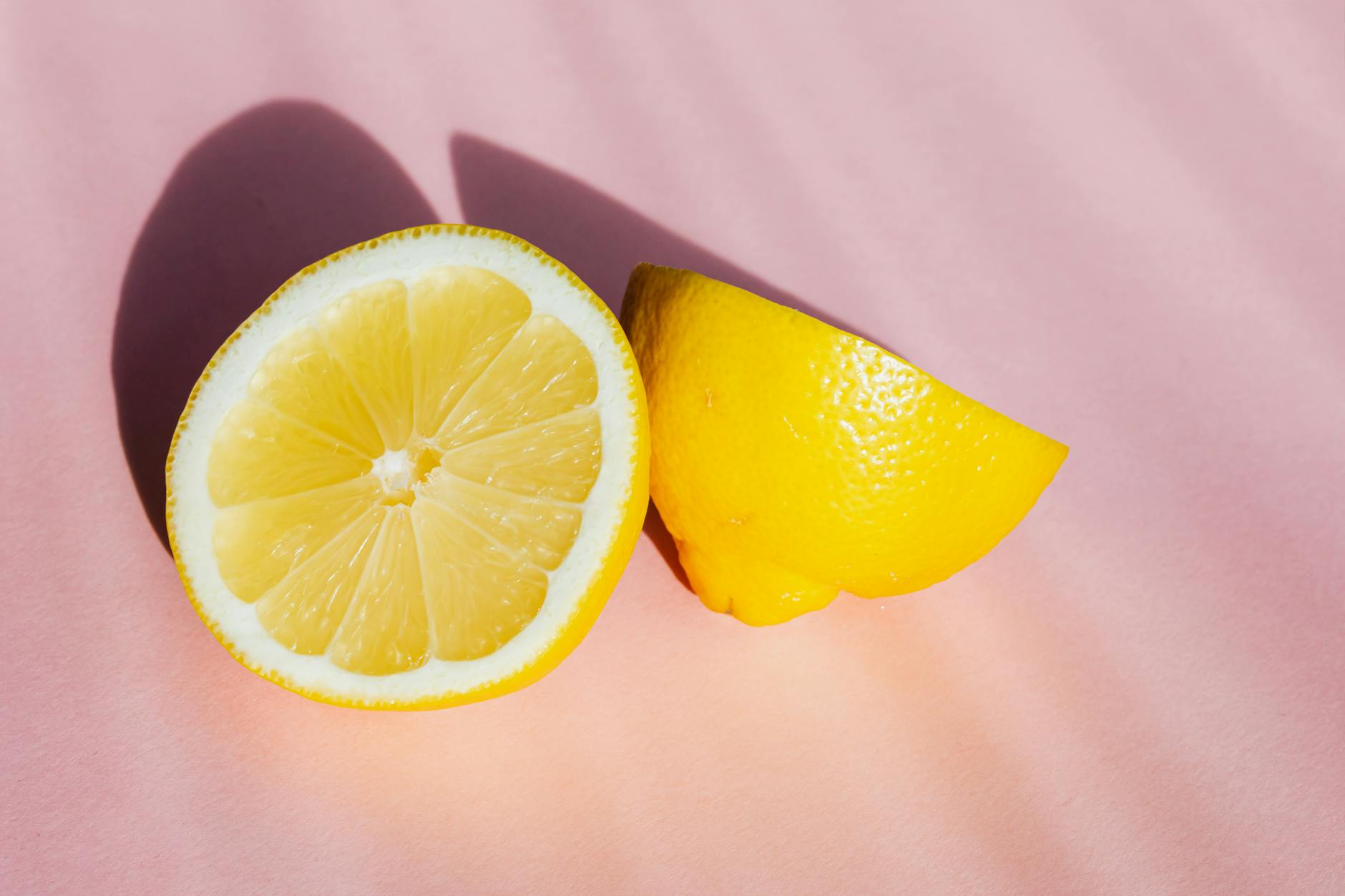 Fresh lemons on a pink background in sunlight