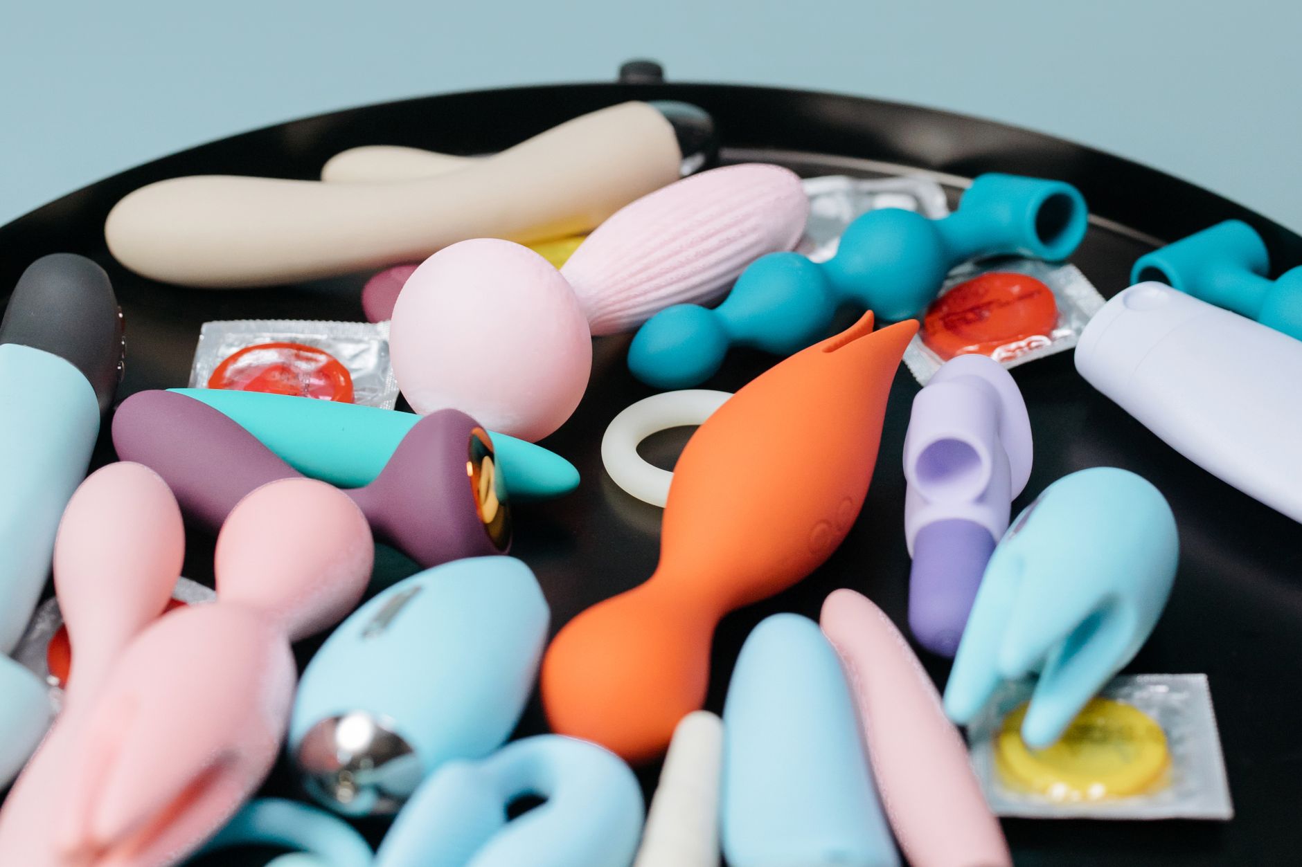 A vibrant collection of various lemon vibrators and sex toys on a black tray, featuring diverse shapes and colors.
