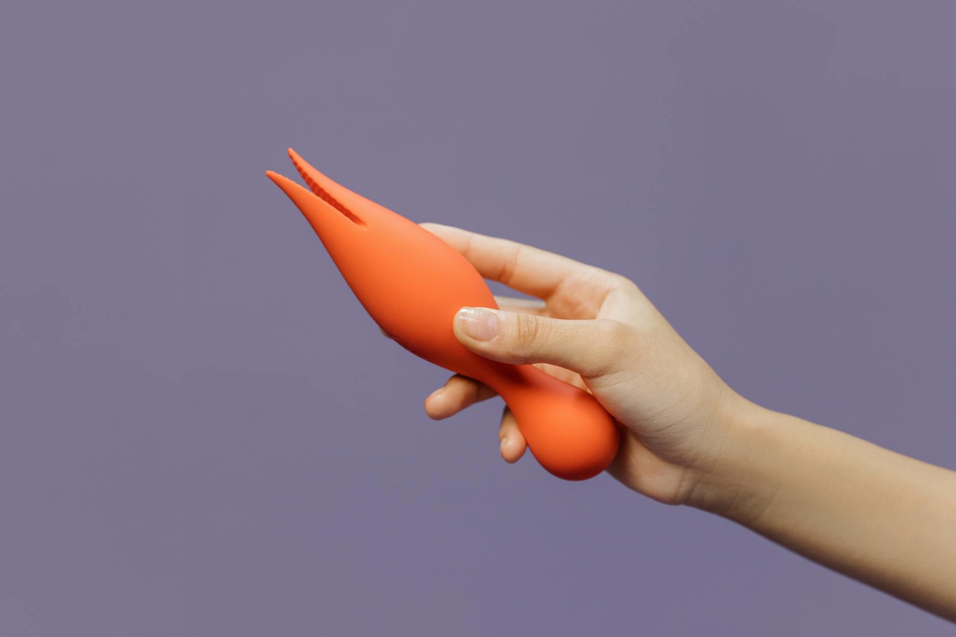 Close-up of a hand holding a lemon vibrator against a minimalistic purple backdrop, showcasing modern sensuality