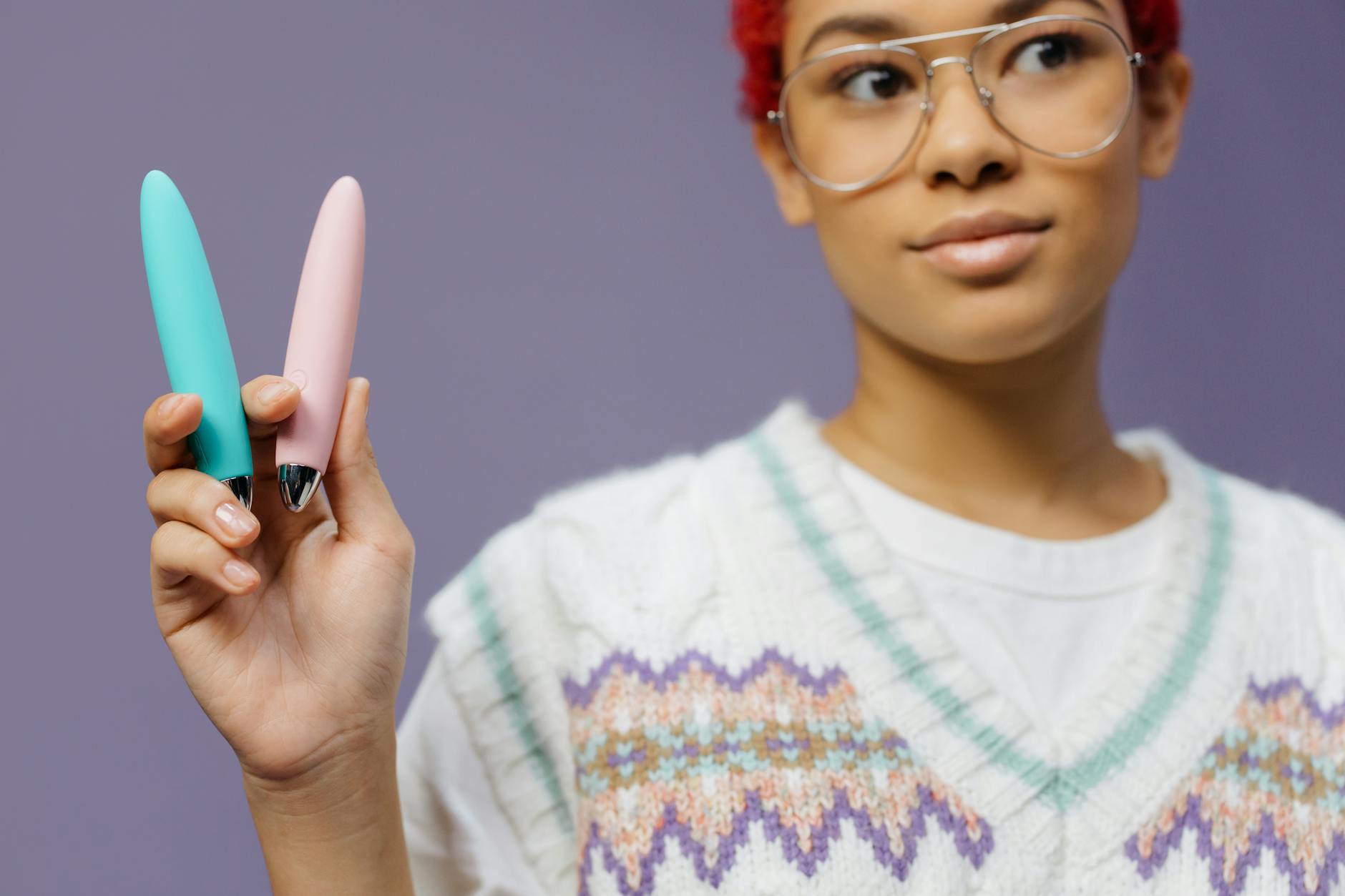 Woman holding colorful vibrators with confident expression