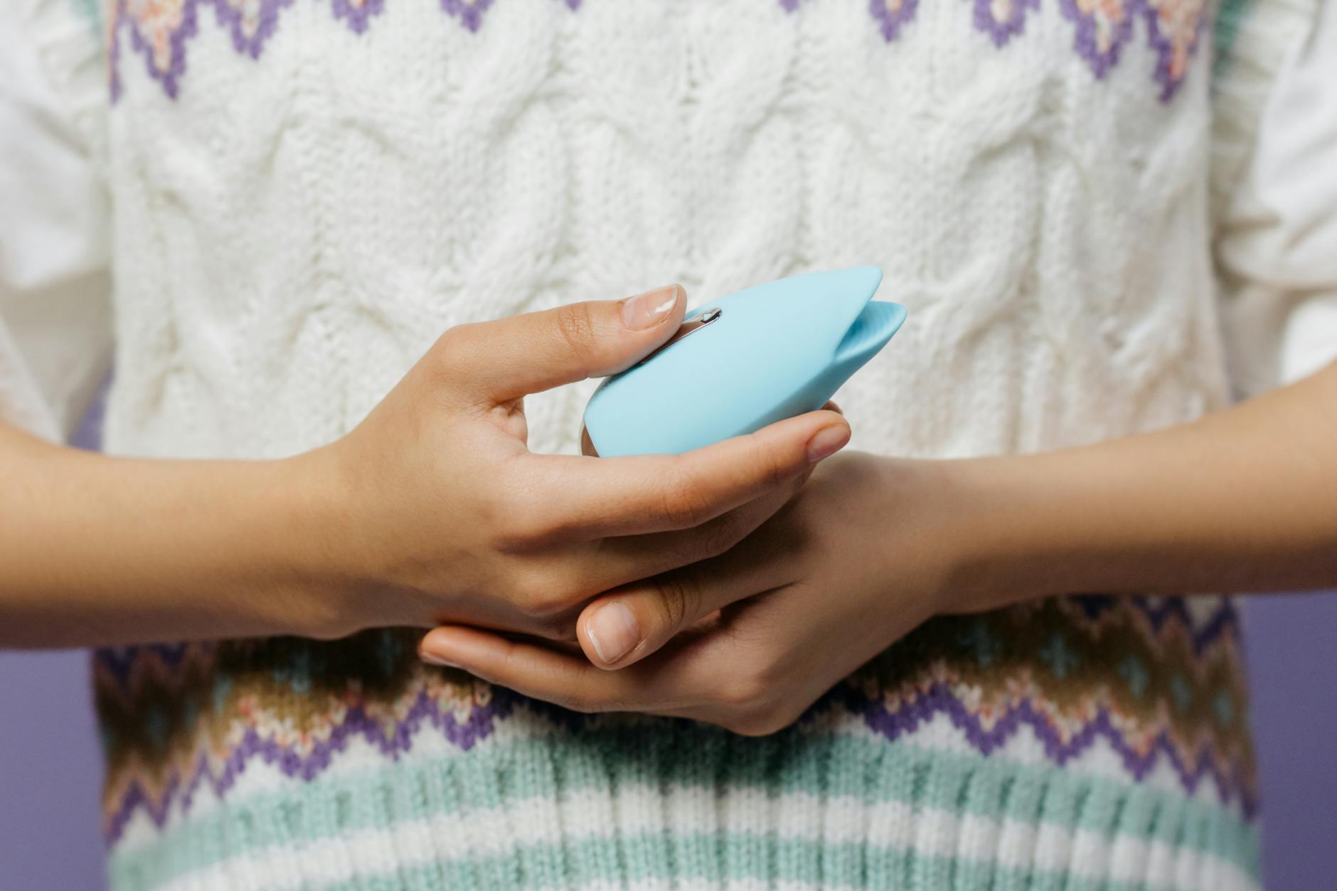 Close-up of hands holding a blue personal massager, symbolizing gentle control and safe exploration