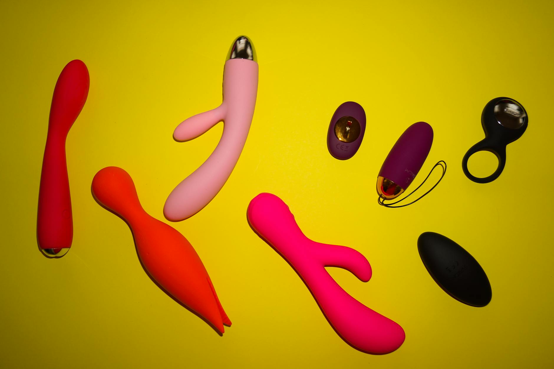 Yellow silicone lemon vibrator surrounded by fresh lemons on a bright yellow background